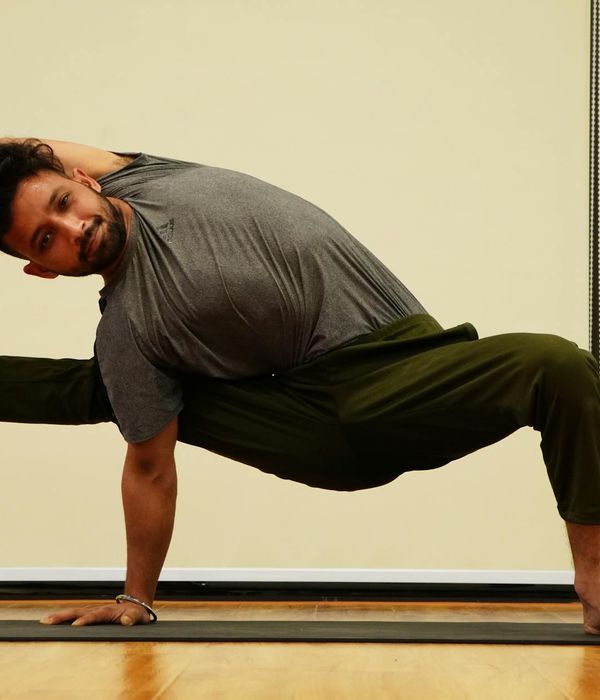 A man holding a challenging balance pose, demonstrating focus and core strength.